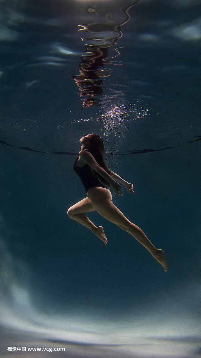 Portrait of young female model underwater in swimming pool.