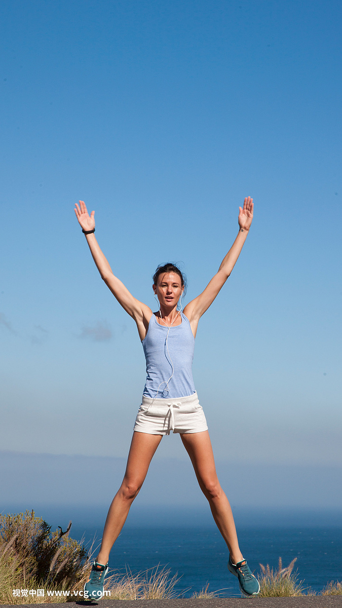 Sport Woman Jumping Mid-air against Ocean and Blue Sky