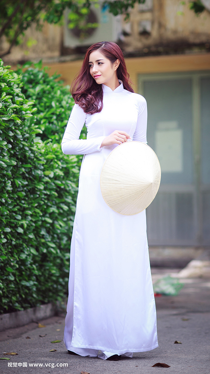 美丽的越南妇女与传统的衣服(ao dai)与棕榈叶锥形帽子